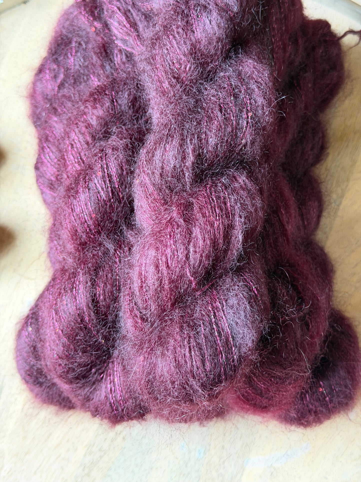 Fil super kid mohair prune profond à paillettes irisées roses et vertes, gros plan, laine Aura Wooliette